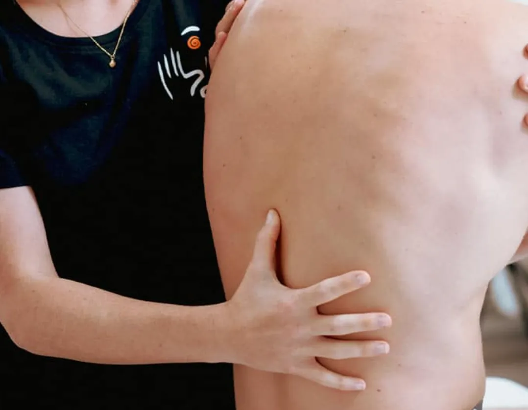 Werknemer van De Fyiso Man die een klant helpt met klachten aan de rug